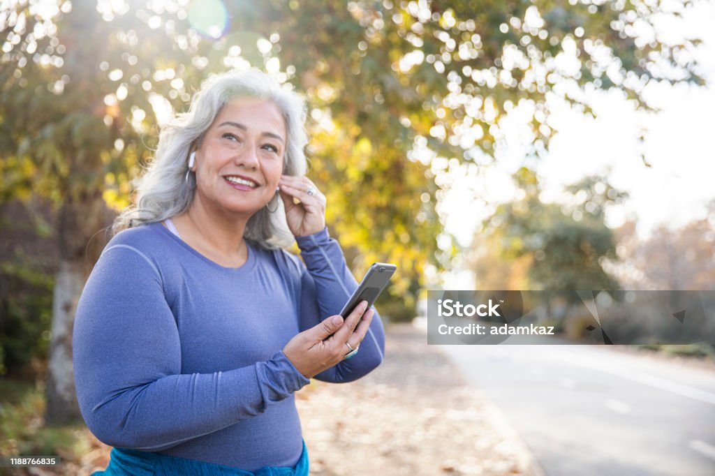 Beautiful Woman With Smartphone Getting Ready for Workout A Mexican woman getting ready to workout Exercising Stock Photo