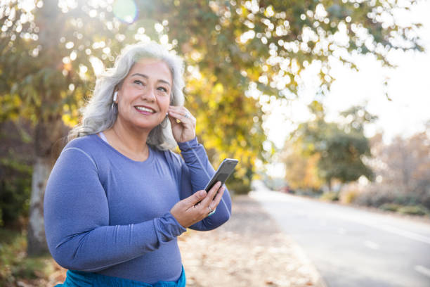 красивая женщина со смартфоном готовится к тренировке - senior adult running jogging senior women стоковые фото и изображения