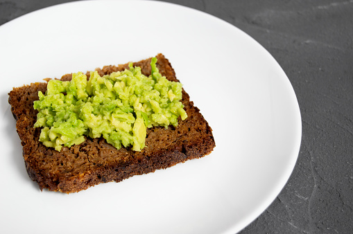 Rustic toast with smash avocado and cereal bread on plate and concrete