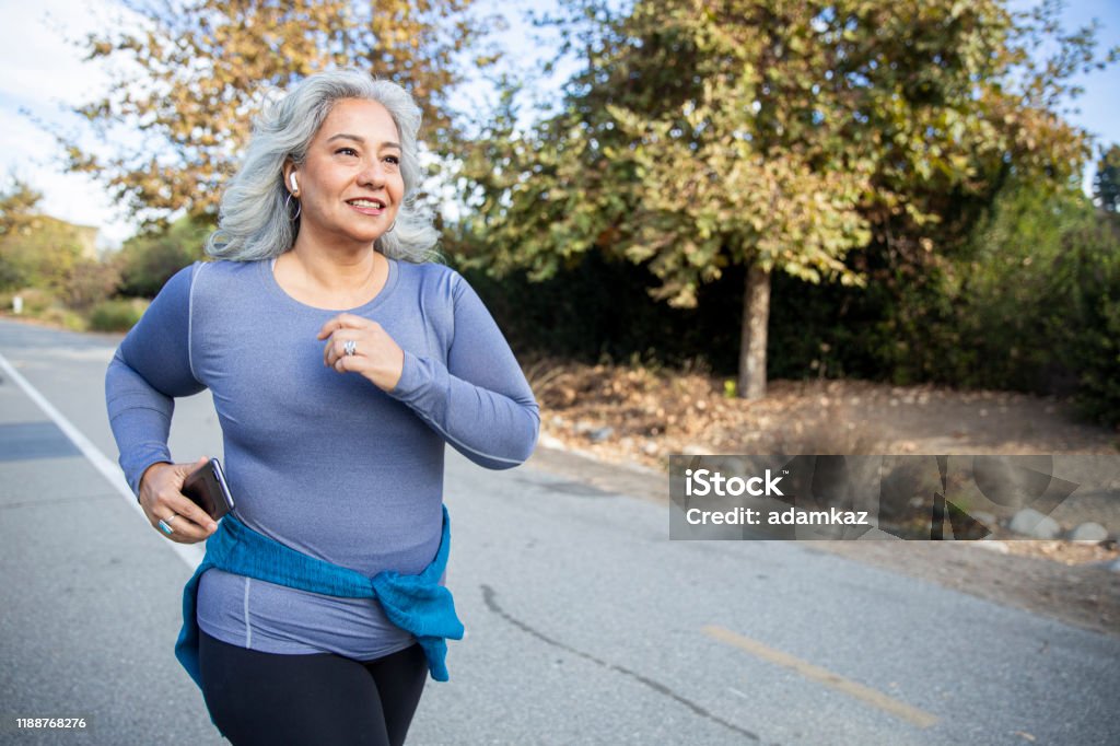 Mexican Woman Jogging A mature Mexican woman jogging on a trail Exercising Stock Photo