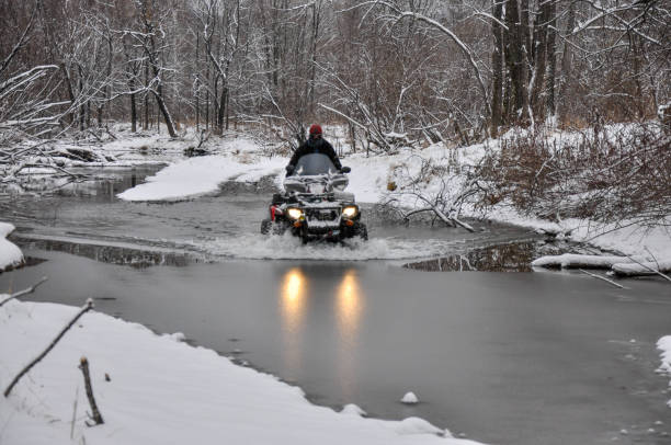 atv na kołach przecina zamarznięty lód łamiący rzekę - off road vehicle quadbike 4x4 adventure zdjęcia i obrazy z banku zdjęć