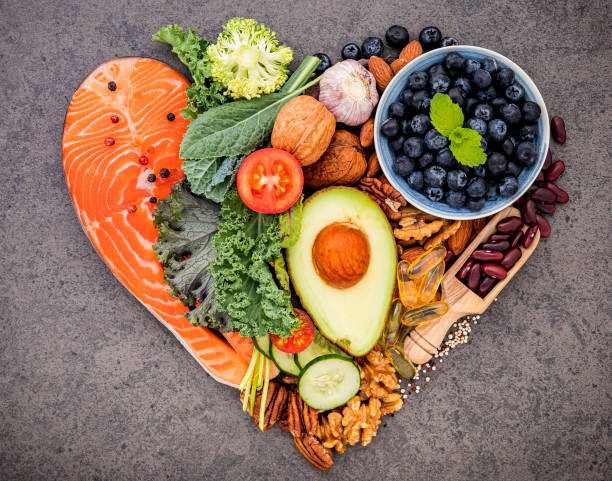 Heart shape of ketogenic low carbs diet concept. Ingredients for healthy foods selection on dark stone background. Balanced healthy ingredients of unsaturated fats for the heart and blood vessels. forma cardíaca de concepto de dieta cetogénica baja en carbohidratos. ingredientes para la selección de alimentos saludables sobre fondo de piedra oscura. ingredientes saludables equilibrados de grasas insaturadas para el corazón y los vasos sanguíneo