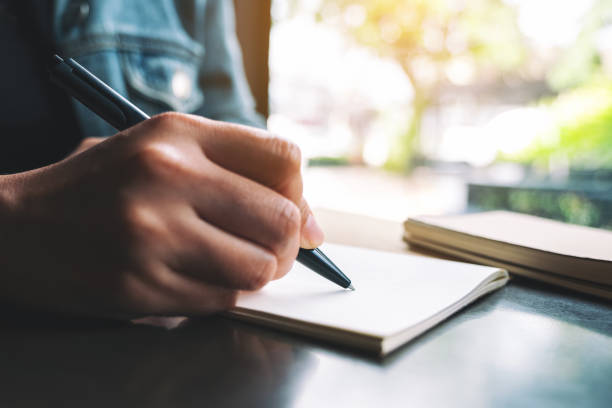 istock a woman writing on a blank notebook on the table 1188774682