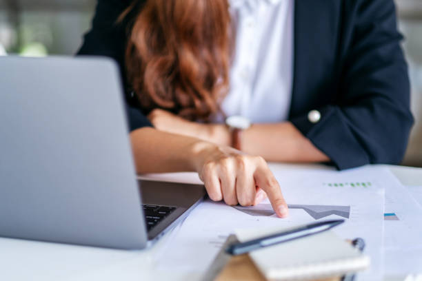 istock businesswoman pointing finger at paperwork while working on laptop in office 1188774694