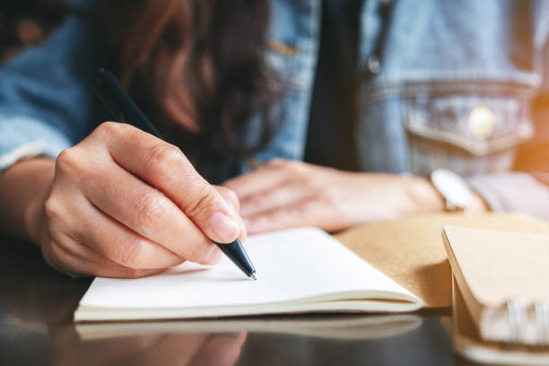 istock a woman writing on a blank notebook on the table 1188774710