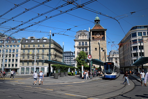 Downtown Geneva tram station with buildings, lines, and people