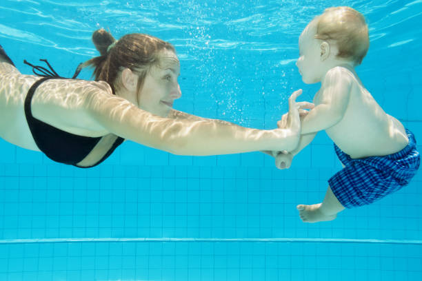 istock Child with mother dive in swimming pool 1188790798