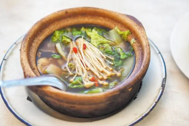 Bak kut teh or Hokkiens topping with golden needle mushroom or Enokitake in Earthenware pot in broth popularly served in Malaysia ,Singapore and and Southern Thailand.