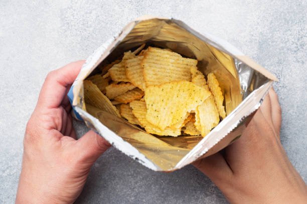 patatas fritas con picante en un paquete abierto, sostén de la mano. cierre enfoque selectivo. - patatas fritas de churrería fotografías e imágenes de stock