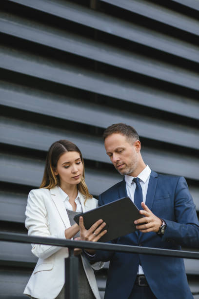 istock Two business people discussing work on tablet computer outdoors 1188805144