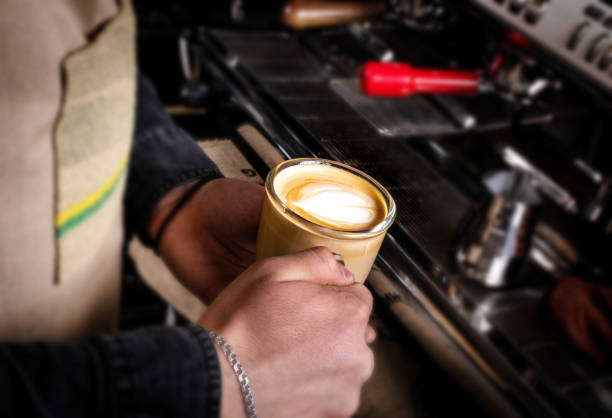 Barista makes latte coffee with milk in cafe closeup