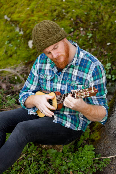 istock Hipster man with red beard playing a ukulele 1188822261