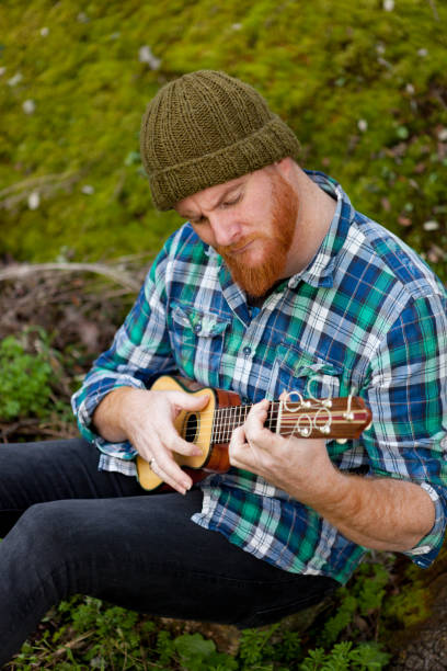istock Hipster man with red beard playing a ukulele 1188822275