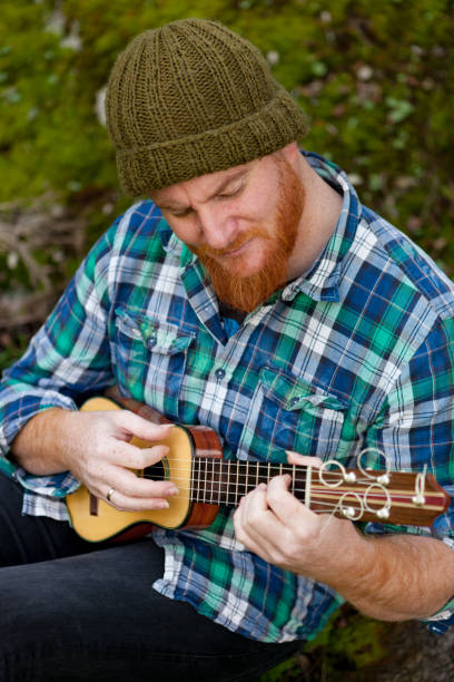 istock Hipster man with red beard playing a ukulele 1188822278
