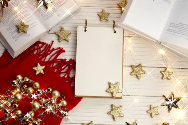 istock Christmas to-do list.Winter layout. Winter holidays mockup. Empty notebook with red knitted scarf and books, gold stars and shining garlands on a white wooden background.copy space.Winter holidays 1188823239