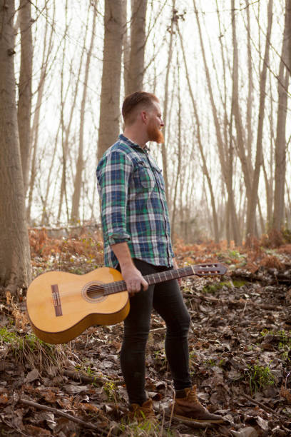 istock Pensive red haired man holding a guitar in the forest 1188825184