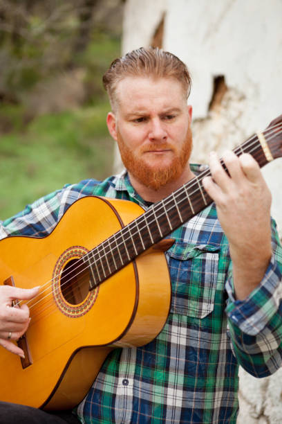 istock Hipster man with red beard playing a guitar 1188825920