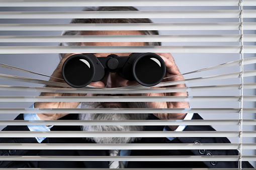 Senior businessman peeking throuth blinds