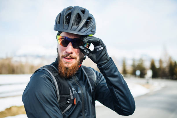 Front view of mountain biker with sunglasses standing outdoors in winter nature.