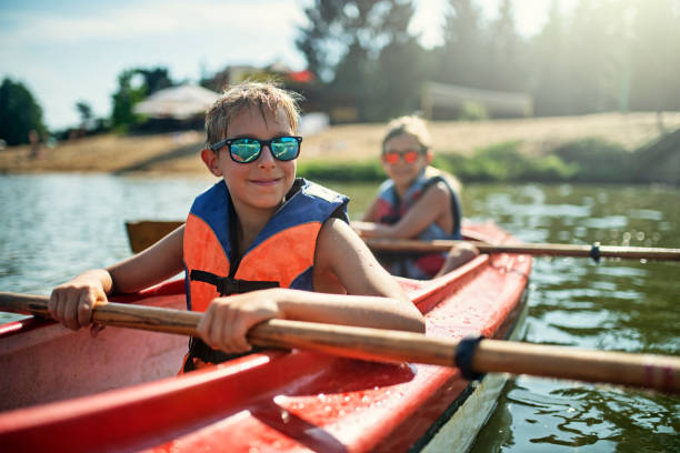 dos chicos disfrutando del kayak en el lago - seguridad fotos fotografías e imágenes de stock