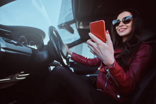 istock Young pretty woman is siting in her car while chatting on mobile phone 1188830277