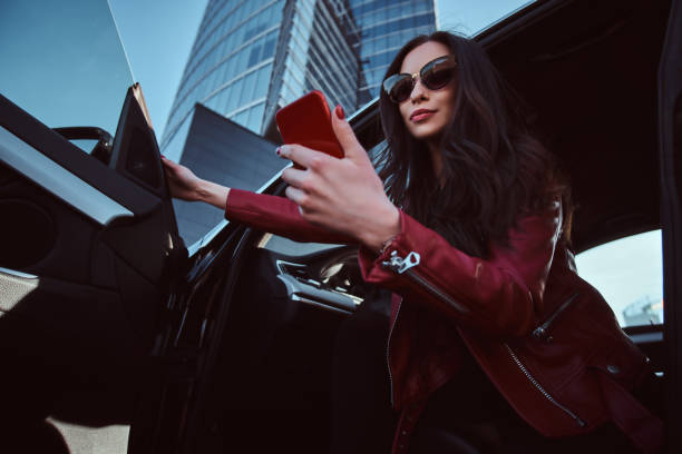 istock Beautiful smart women is posing in her new car while chatting on mobile phone 1188832003