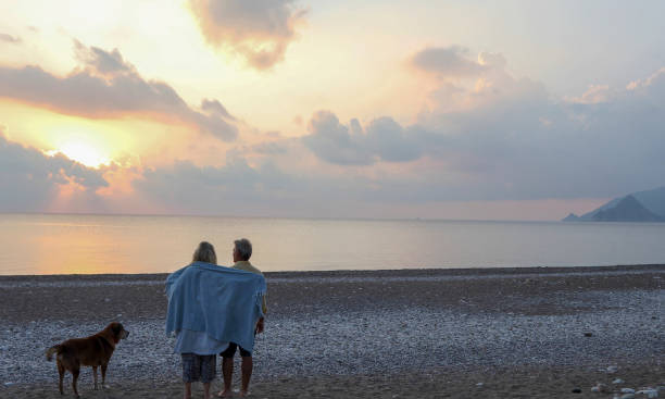 istock Couple walks along empty beach at sunrise 1188834320