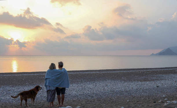istock Couple walks along empty beach at sunrise 1188834876