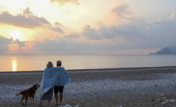 istock Couple walks along empty beach at sunrise 1188834884