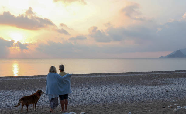 istock Couple walks along empty beach at sunrise 1188834960