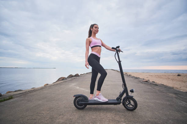 istock Pretty woman is driving her scooter by seashore 1188836136