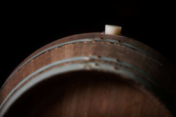 Close up shot of a wooden barrel in a dark wine cellar.