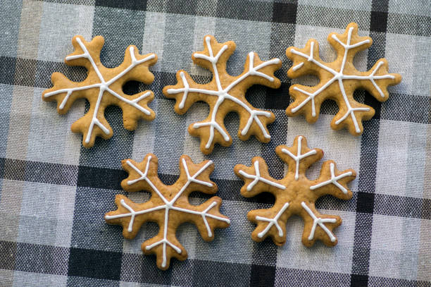 istock Painted traditional Christmas gingerbreads arranged on checkered tablecloth, group of snowflakes, white sugar icing 1188838112