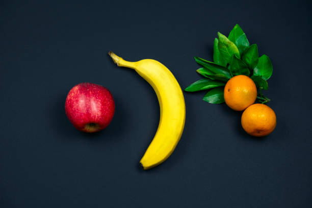 istock apple, banana and tangerines on a black background 1188840793