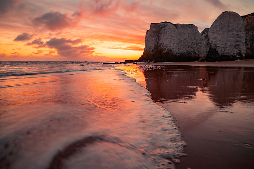 Chalk cliffs and lapping tide at Botany Bay, Margate UK during a beautiful orange sunrise