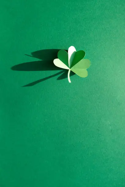 St. Patrick's day, Green Shamrock from paper on green background. Close up. Trend shadow