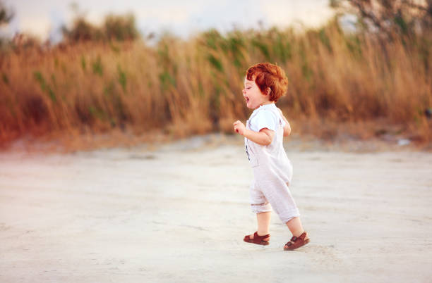 istock delighted redhead toddler baby boy walking outdoors, at summer field 1188842586