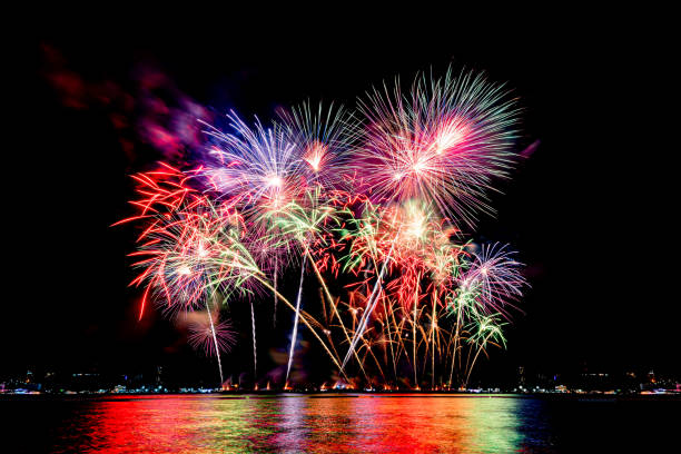 Amazing beautiful colorful fireworks display on celebration night, showing on the sea beach with multi color of reflection on water stock photo