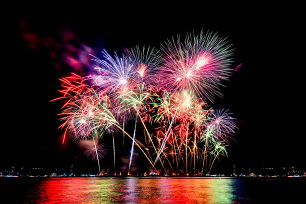 Photo of Amazing beautiful colorful fireworks display on celebration night, showing on the sea beach with multi color of reflection on water