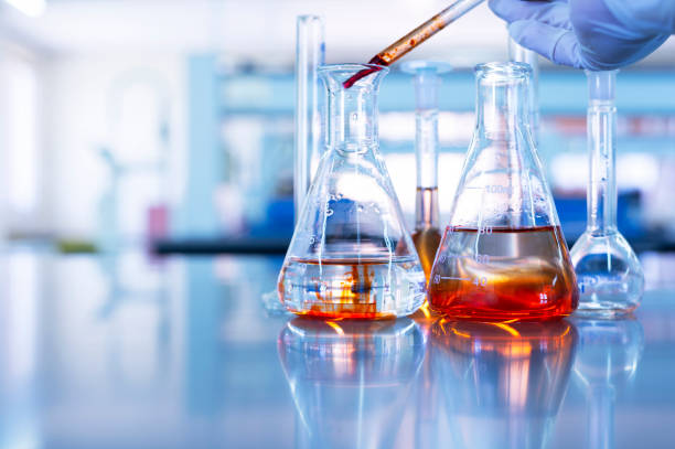 istock hand of scientist drop orange solution in glass flask in chemistry science laboratory blue background 1188843643
