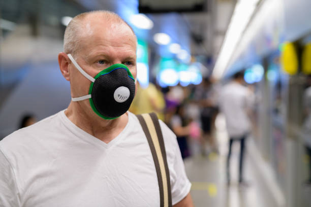 istock Senior man using face mask to protect from pollution smog in city 1188844296