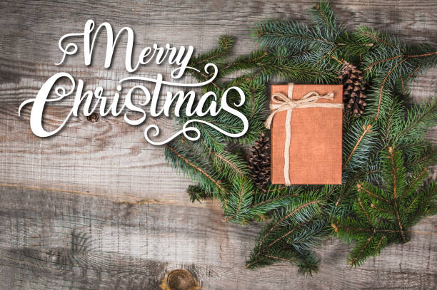 istock Present bow surrounded by tree branches on a wooden table with the text Merry Christmas 1188844400
