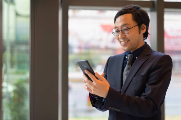 istock Happy Asian businessman using phone by the window 1188844539