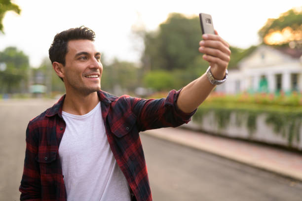 istock Happy young handsome Hispanic hipster man taking selfie at the park 1188845480