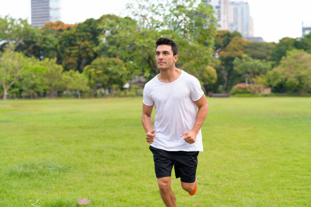 Portrait of young handsome Hispanic man in the park outdoors