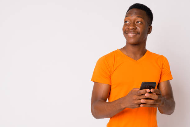 Portrait of young happy African man thinking while using phone