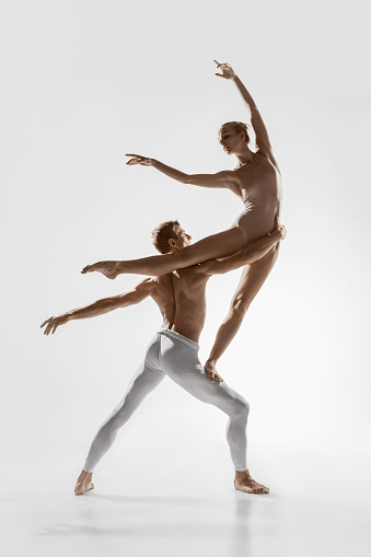 Wings growth. Couple of modern ballet dancers isolated on white background. Contemporary art ballet. Young flexible athletic man and woman dancing. Grace, motion, flexibility, inspiration concept.