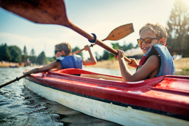two boys enjoying kayaking on lake - lake imagens e fotografias de stock