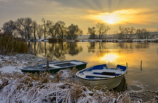 Old lonely motorboat in a frozen harbour in winter, snowy landscape, plenty of copy space on top