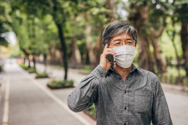 istock Man with surgical mask talking on mobile on the street 1188853702